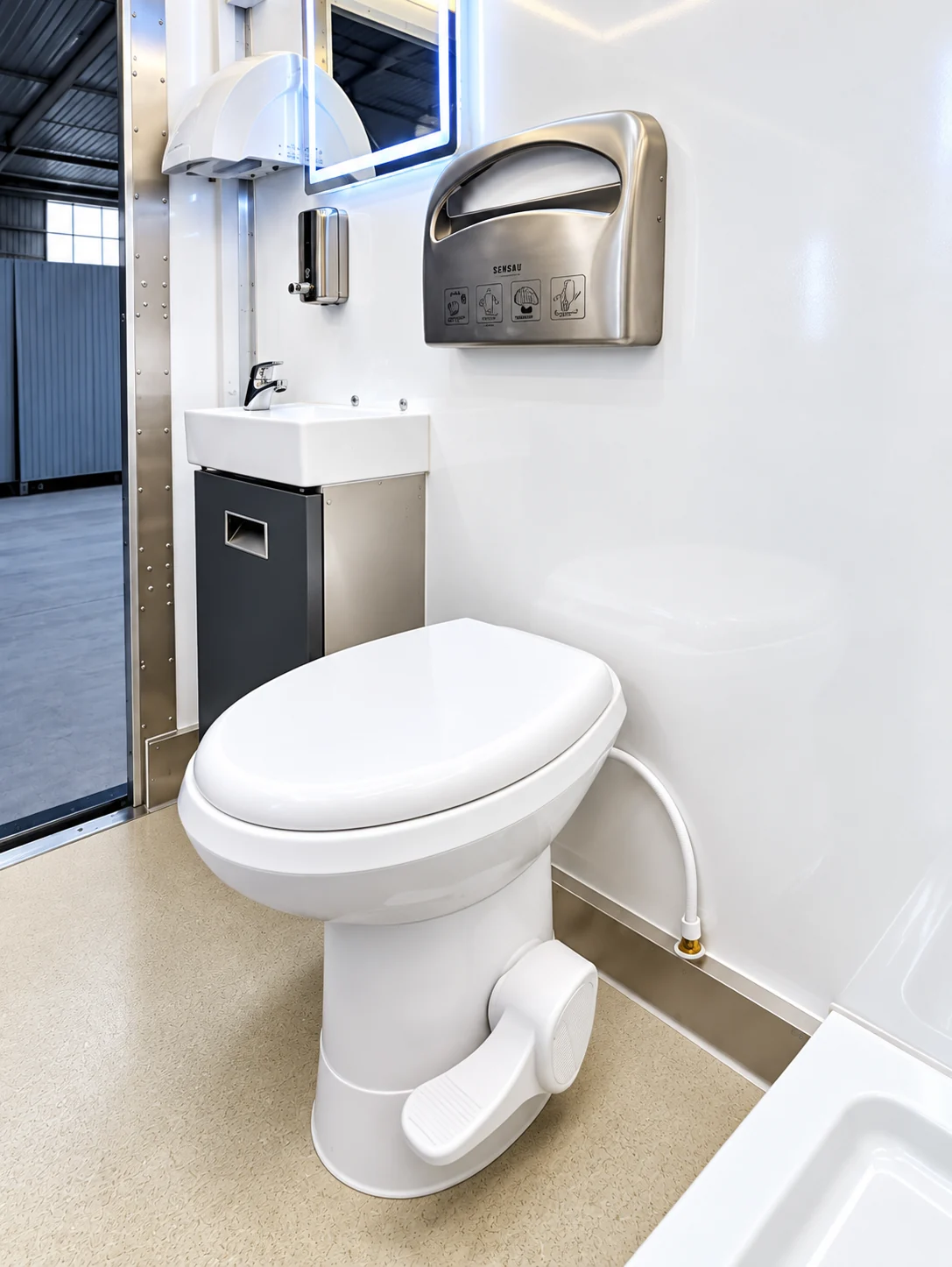 Restroom compartment with a toilet, washbasin and wall-mounted dispensers