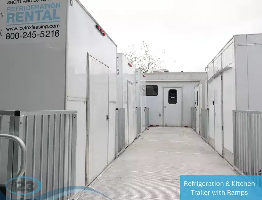 Refrigerated and kitchen rental trailers with ramps, lined up along a walkway with access doors on both sides.